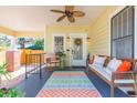 Inviting front porch with a ceiling fan, seating, and colorful rug creating a cozy outdoor living space at 907 E Hamilton Ave, Tampa, FL 33604