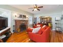 Cozy living room featuring hardwood floors, a brick fireplace, comfortable seating, and an open layout at 907 E Hamilton Ave, Tampa, FL 33604