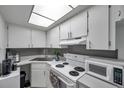 Bright kitchen featuring white cabinets, gray backsplash, and modern appliances at 100 Waverly Way # 101, Clearwater, FL 33756