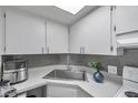 Bright kitchen featuring white cabinets, gray backsplash, and modern appliances at 100 Waverly Way # 101, Clearwater, FL 33756