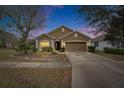 Charming one story home featuring a two car garage, neutral paint, and manicured landscaping at twilight at 10328 Celtic Ash Dr, Ruskin, FL 33573