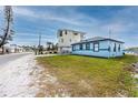 The home has a light blue exterior and sits on a lush green lawn with waterfront views at 14050 W Parsley Dr, Madeira Beach, FL 33708