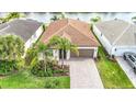One-story home featuring a well-manicured lawn, tile roof, two-car garage, paver driveway and lush landscaping at 15434 Santa Pola Dr, Wimauma, FL 33598