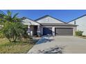 Inviting home featuring a two-car garage, covered porch, and low maintenance landscaping at 197 Rain Berry Ave, Ruskin, FL 33570