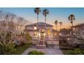 Elegant home featuring a grand entrance with stairs, lush landscaping, and soaring palm trees under a beautiful sunset sky at 2077 N Pointe Alexis Dr, Tarpon Springs, FL 34689