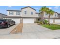 Townhome with garages, concrete driveways, stone accents, palm trees, and front yard at 21181 Threadfin Way, Land O Lakes, FL 34638