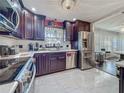Kitchen features stainless steel appliances, dark wood cabinets, marble tile flooring, and a window overlooking the backyard at 110 Aspen Cir, Seminole, FL 33777