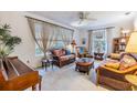 Bright living room with wicker furniture, large windows with drapes, and a ceiling fan at 1421 Monte Carlo Dr, Clearwater, FL 33764