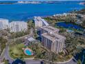 Stunning aerial view of a waterfront condominium complex with a pool, surrounded by lush greenery and water views at 150 Belleview Blvd # 307, Belleair, FL 33756