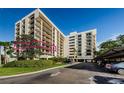 Modern high-rise condo building with multiple balconies and covered parking under a clear blue sky at 150 Belleview Blvd # 307, Belleair, FL 33756