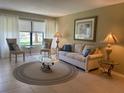 Cozy living room features neutral tones, comfortable seating, and a serene view through large windows at 1750 Belleair Forest Dr # A7, Belleair, FL 33756