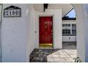 Elegant red front door with decorative details, set in a white stucco wall and brick paved entrance at 2100 Mcmullen Rd, Largo, FL 33771