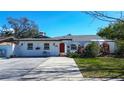 Charming white single-story home with red door, neat landscaping, and a spacious driveway at 2100 Mcmullen Rd, Largo, FL 33771