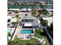 Aerial view of home with private pool, fenced yard, solar panels and waterfront views at 2504 Bayshore Dr, Belleair Beach, FL 33786