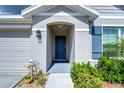 Charming home featuring a blue front door and light gray exterior, complemented by well-maintained landscaping at 38255 Sonnet Landing Ave, Zephyrhills, FL 33540