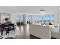Bright, spacious living room with modern chandelier, piano, and panoramic water views at 450 Knights Run Ave # 1704, Tampa, FL 33602