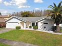 Inviting one-story home with green lawn, minimalist landscaping, palm tree, and a two car garage at 4735 Foxshire Cir, Tampa, FL 33624
