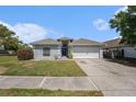 Charming single-Gathering home featuring a well-maintained lawn, driveway, and two-car garage under a clear sky at 8941 Southbay Dr, Tampa, FL 33615