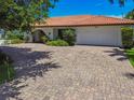 Charming single-story home featuring a tile roof, brick driveway, and well-manicured landscaping at 205 Harrison Ave, Belleair Beach, FL 33786