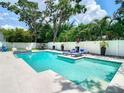 Backyard swimming pool with lounge chairs, table and chairs with manicured tropical landscaping and privacy fence at 4816 W San Jose St, Tampa, FL 33629