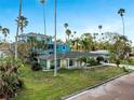 Charming single-story home featuring large windows, a well-kept lawn, and mature palms at 100 Buena Vista S Dr, Dunedin, FL 34698