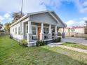 Charming single-story home featuring a welcoming front porch, orange door, well-manicured lawn, and a long driveway at 1003 W Reynolds St, Plant City, FL 33563