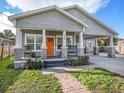 Charming single-story home featuring a welcoming front porch, orange door, well-manicured lawn, and a brick walkway at 1003 W Reynolds St, Plant City, FL 33563