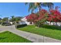 Landscaped front yard with flowering tree and mature shrubbery leads to a single-Gathering home with a two-car garage at 11218 Longbrooke Dr, Riverview, FL 33579