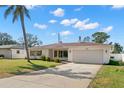 Charming single-story home featuring a well-manicured lawn, a long driveway, and an attached two-car garage at 1974 Valencia Way, Clearwater, FL 33764