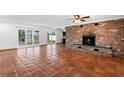 Spacious living room with terracotta tile flooring, a brick fireplace, and sliding glass doors that offer natural light at 1974 Valencia Way, Clearwater, FL 33764