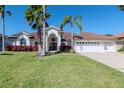 Beautiful home featuring a well-maintained lawn, mature palm trees, and a spacious three-car garage at 6014 Mariners Watch Dr, Tampa, FL 33615