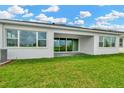 Backyard view with large sliding glass door, covered patio, lush green grass, and neutral colored walls at 10432 Torchwood Sea Way, San Antonio, FL 33576