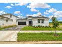 Attractive single-story home with green lawn, two-car garage and long paver driveway with bright blue sky at 10432 Torchwood Sea Way, San Antonio, FL 33576