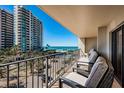 Relaxing balcony overlooking a beautiful beach, lush landscaping, a nearby pool, and a neighboring building at 1480 Gulf Blvd # 410, Clearwater Beach, FL 33767