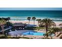 Inviting community pool on the beach with lounge chairs, a tiki hut, and swaying palm trees at 1480 Gulf Blvd # 410, Clearwater Beach, FL 33767