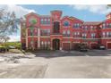 Attractive red condo building featuring covered garages and well-kept grounds with palm trees at 2713 Via Murano # 216, Clearwater, FL 33764