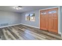 Bright and airy living room featuring modern gray flooring, a window, and a wooden front door at 3048 Holiday Lake Dr, Holiday, FL 34691
