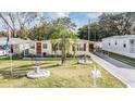 Attractive yellow home with red shutters, complemented by a well-maintained lawn, palm tree, and decorative features at 36936 Kay Ave, Zephyrhills, FL 33542