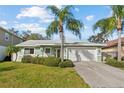Charming single-story home featuring a two-car garage, well-manicured lawn, and mature palm trees at 45 Gulfwinds W Dr, Palm Harbor, FL 34683