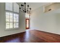 Open-concept living room with hardwood floors, chandelier, and decorative window with privacy shutters at 10614 Chambers Dr, Tampa, FL 33626