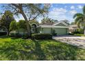 Charming single-story home with a lush green lawn, inviting curb appeal, and a brick-paved driveway at 1514 River Ct, Tarpon Springs, FL 34689