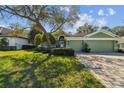 Charming single-story home with a lush green lawn, inviting curb appeal, and a brick-paved driveway at 1514 River Ct, Tarpon Springs, FL 34689