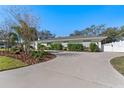 Well-maintained exterior featuring a long driveway and manicured landscaping against a clear blue sky at 1664 Sharon Way, Clearwater, FL 33764