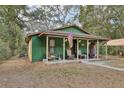 Charming green home featuring a cozy front porch with rocking chairs at 303 Grand Ave, Brooksville, FL 34604