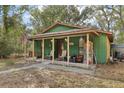 Green house with a welcoming front porch, rocking chairs, and rustic charm at 303 Grand Ave, Brooksville, FL 34604
