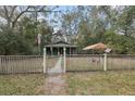 Charming green home with a covered porch, fenced yard, and mature trees at 303 Grand Ave, Brooksville, FL 34604