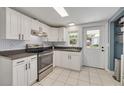 Bright kitchen features white cabinets, stainless steel appliances, tile backsplash, and backyard access at 305 6Th Sw Ave, Largo, FL 33770