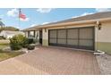 Single-story home featuring a brick driveway, well-maintained landscaping, and American flag at 335 Stroll Ln, Sun City Center, FL 33573