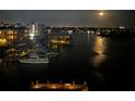 Night view of the marina showcasing the lights of the city and full moon with boats docked in the water at 10355 Paradise Blvd # 909, Treasure Island, FL 33706