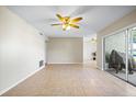 Open living room with tile floors, neutral walls, ceiling fan, and sliding glass doors to an outdoor area at 11407 3Rd N St # 1, St Petersburg, FL 33716